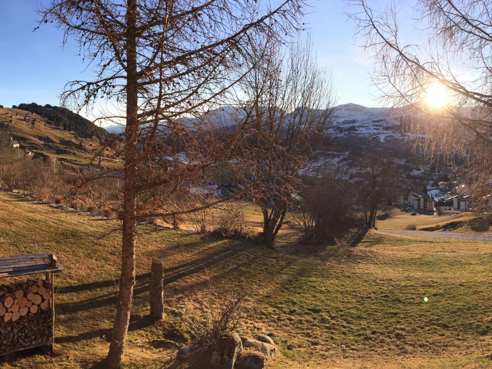 Abendlicht über Brigels — Blick aus dem Garten der Casa Seglias auf das Dorf und die schneebedeckten Berge