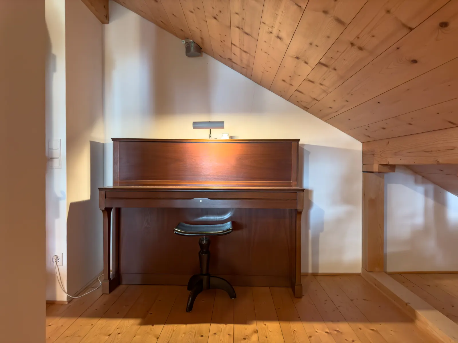 Das Klavier unter der geneigten Holzdecke im Dachgeschoss