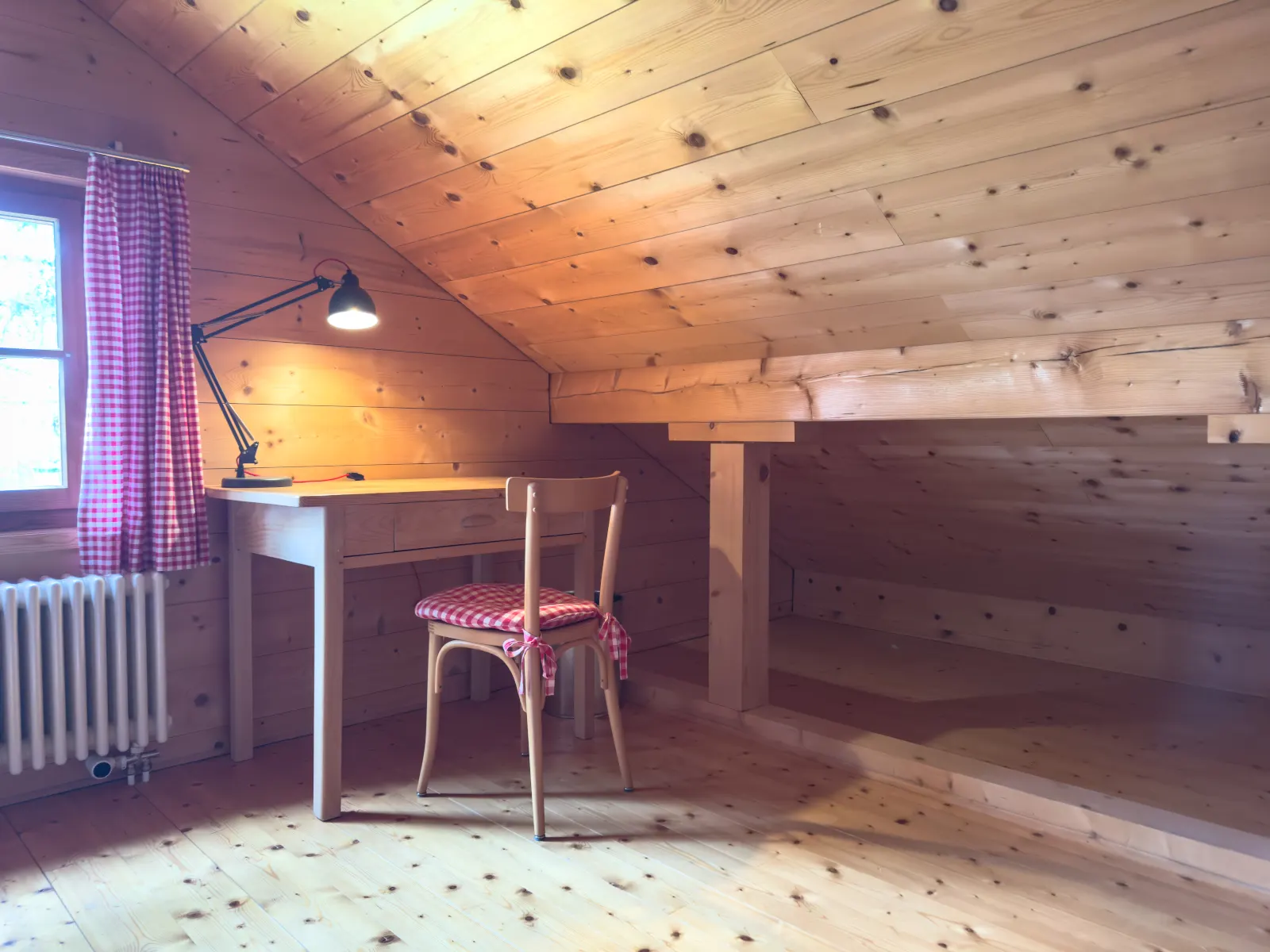Schreibtischecke im Dachgeschoss mit Lampe und rot kariertem Stuhlkissen